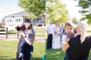 Image of photographer holding child while taking wedding pictures
