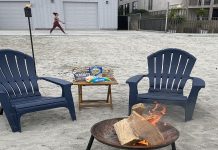 Two chairs and a table with smores ingredients are set up near a bonfire