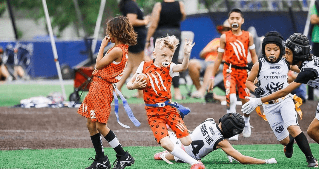 boy running with football during flag football game